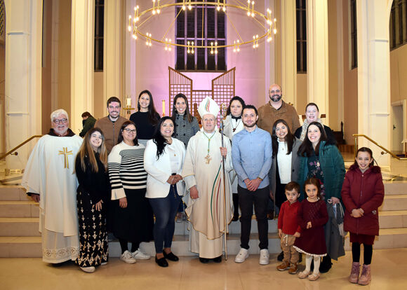 Edina Teopoldo de Campos (to the left of Bishop Fintan) and Danilo Fraga Peixoto (to the right of the bishop) are pictured with families and friends after they were baptised and confirmed at the Easter Vigil. (Photo: Mike English).
